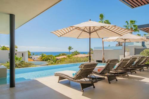 a group of chairs and umbrellas next to a swimming pool at Villa Real para 12 personas con piscina privada in Cabo San Lucas