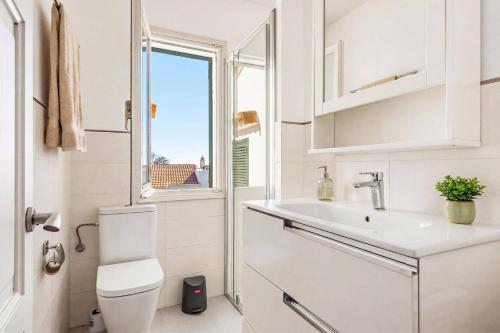 a bathroom with a toilet and a sink and a window at Villa Caprice by Villa Plus in S'Algar