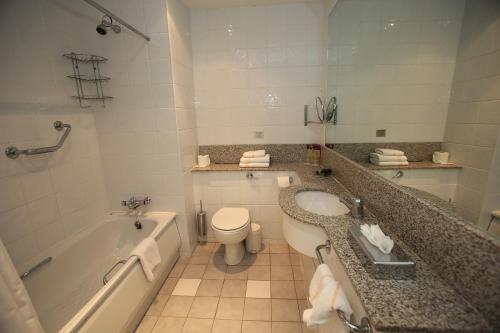 a bathroom with a tub and a toilet and a sink at Killarney Riverside Hotel in Killarney