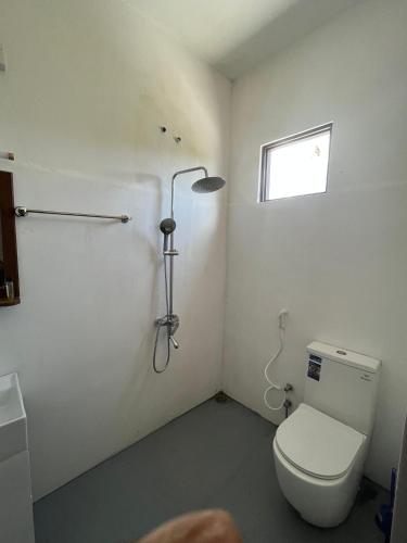 a bathroom with a toilet and a shower and a window at Bella Sunset Point in Embilipitiya
