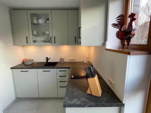 a kitchen with white cabinets and a statue of a chicken on the counter at Ferienhaus Uferweg in Otterndorf