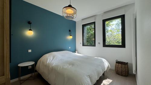 a bedroom with a white bed and two windows at Villa Koad - piscine privee in Trébeurden