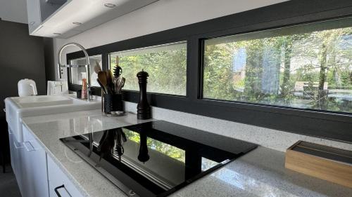 a kitchen with a sink and two windows at Villa Koad - piscine privee in Trébeurden