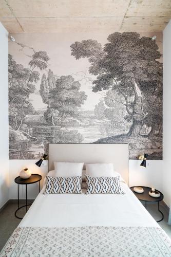 a bedroom with a white bed and a wall mural at Apartamentos Territorios in Mérida