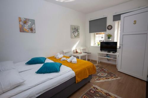 a bedroom with a bed with blue pillows and a television at Bosanska Avlija Authentic Sarajevo Stay with Garden in Sarajevo