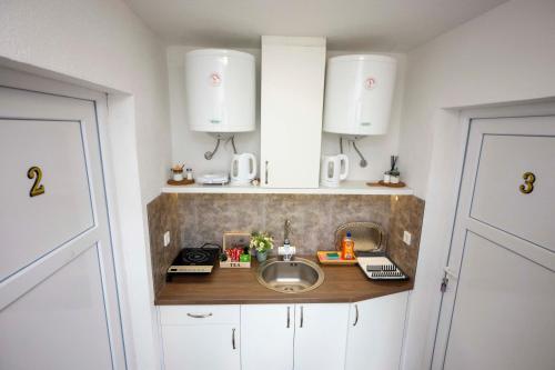 a small kitchen with a sink and white cabinets at Bosanska Avlija Authentic Sarajevo Stay with Garden in Sarajevo