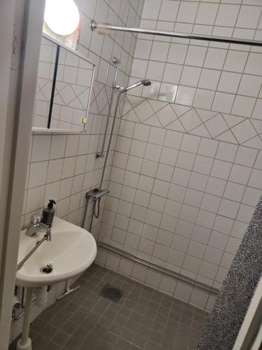 a white tiled bathroom with a sink and a shower at Karl Cozy stay in Örebro