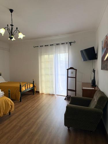a living room with a couch and a bed and a television at Casa de São Luís - Turismo Rural in Torre de Moncorvo