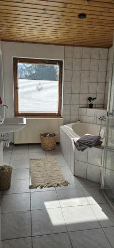 a bathroom with a tub and a sink and a window at Waitzdorfer Landhaus Pieper in Hohnstein