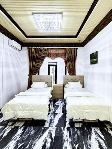 two beds in a room with a ceiling at Bints Guesthouse Syariah in Banjarbaru