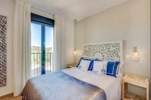 a bedroom with a bed with blue pillows and a window at Can Tau Cala Tarida in Sant Josep de sa Talaia