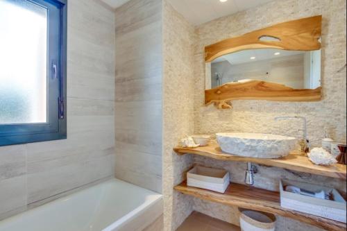 a bathroom with a sink and a tub and a mirror at Can Tau Cala Tarida in Sant Josep de sa Talaia