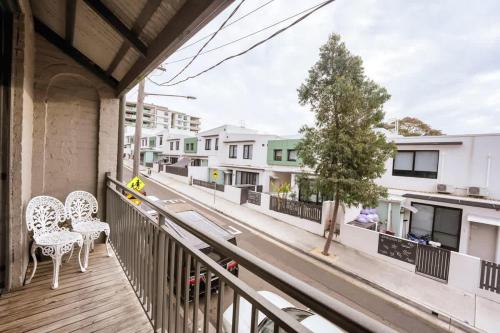 a balcony with two chairs and a tree on a street at 3BR CBD Aircon Redfern family home in Sydney