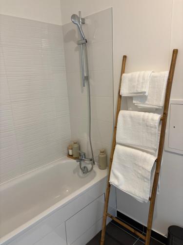 a bathroom with a bath tub and a sink and towels at Cocon Seine parisii in Sartrouville
