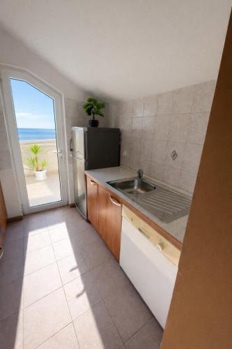 a kitchen with a sink and a refrigerator and a window at Villa Sunce Beachfront in Podgora