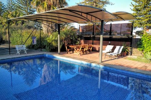 an umbrella over a swimming pool with a table and chairs at Swainson on Lady Gowrie in Largs