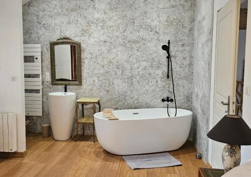 a bathroom with a white tub and a mirror at Les Anges de la Vigne par Lisca Begay in Biron