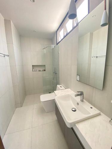 a white bathroom with a sink and a mirror at White Cube House in Nathon Bay