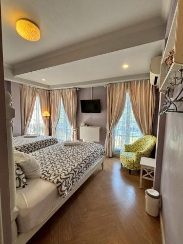 a bedroom with a bed and a chair and windows at Maison Dang Boutique Hotel in Chiang Mai