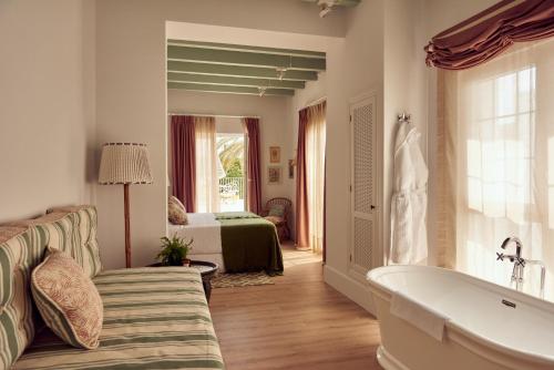 a bathroom with a couch and a tub and a bedroom at Cristine Bedfor Mahon Boutique Hotel in Mahón