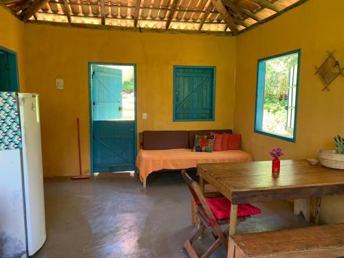 a room with a table and a couch and blue doors at Casa da Roça- Casa completa e jardim privativo in Mata de Sao Joao