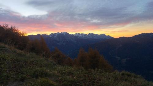 a view of a mountain range with the sun setting at Villetta Val Di Sole in Commezzadura