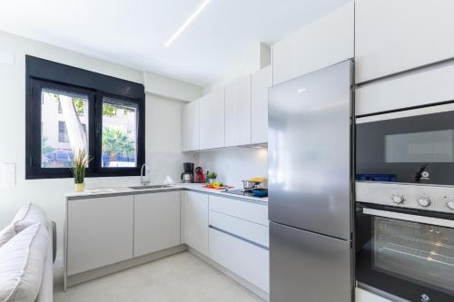 a kitchen with white cabinets and a stainless steel refrigerator at Brisamar Suites I by VillaGranCanaria in Arinaga