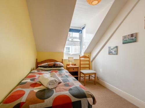 a small attic bedroom with a bed and a chair at 6 Bed in Tenby oc-fb220 in Tenby