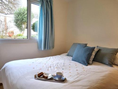 a bed with a tray of food and a window at 2 Bed in Galmpton oc-bx008 in Galmpton-on-the-Dart