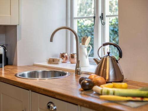 a kitchen counter with a sink and fruits and vegetables at 1 Bed in Moreton -in- Marsh oc-53420 in Blockley