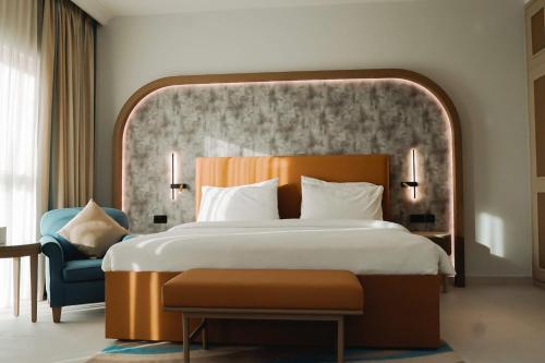a bedroom with a large bed and a blue chair at Sheraton Khalidiya Hotel in Abu Dhabi