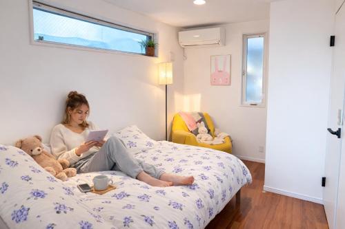 a woman sitting on a bed with a tablet at Ikebukuro area, Close to Shinjuku, three layer house, Viewing terrace, 6 min walk to subway stn, 近池袋新宿 全新三层别墅有露台 地铁站步行6分 直达新宿 东京塔 哈利波特主题乐园 公交站步行3分 最大7人 in Tokyo