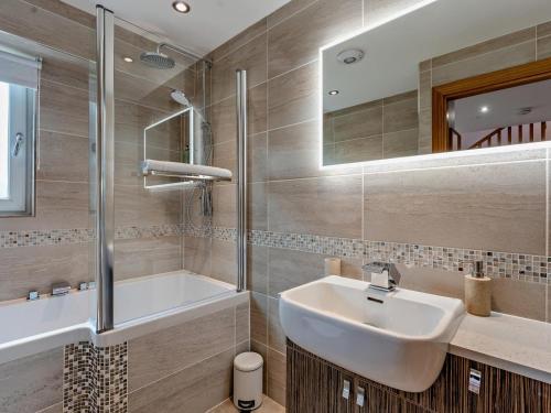 a bathroom with a sink and a tub and a mirror at 2 Bed in Castle Douglas oc-59637 in Castle Douglas