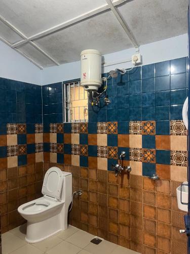 a bathroom with a toilet and a blue tiled wall at Org Retreat & Farmstay in Guwahati
