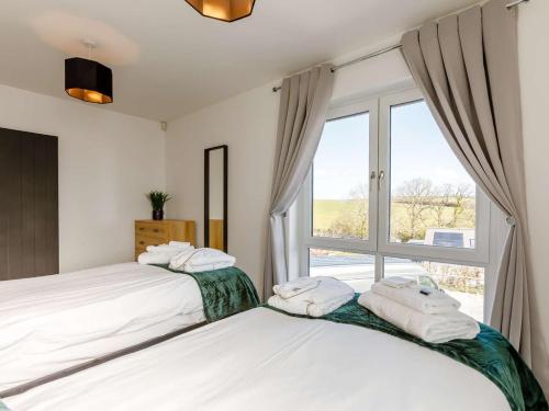 two beds in a bedroom with a window at 4 Bed in Holsworthy oc-85673 in Bridgerule