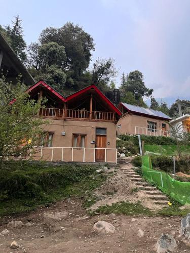 a house on a hill next to a dirt road at Riverside Mudhouse Duplex Cottage by Kahani in Jibhi