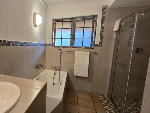 a bathroom with a shower and a tub and a sink at Kruger park lodge 517 in Hazyview