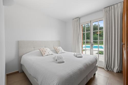 a white bedroom with a large bed and a window at Villa Olivia - Golfe de Saint-Tropez in Cogolin