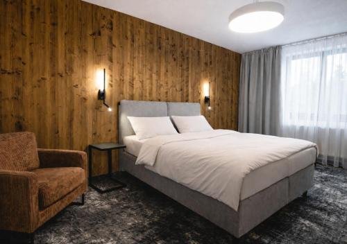 a bedroom with a large bed and a chair at Hotel Horal in Rožnov pod Radhoštěm