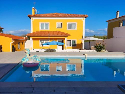 a swimming pool in front of a yellow house at Villa Paraíso Do Coto - Piscina, mar e surf in Coto