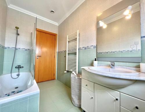 a bathroom with a sink and a tub and a mirror at Villa Paraíso Do Coto - Piscina, mar e surf in Coto