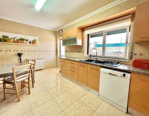 a kitchen with a table and a sink and a counter at Villa Paraíso Do Coto - Piscina, mar e surf in Coto