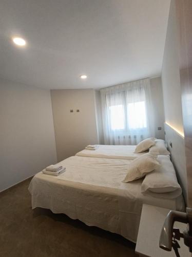 a bedroom with a large bed with white sheets and pillows at Apartamentos Elvira Valderrobres in Valderrobres
