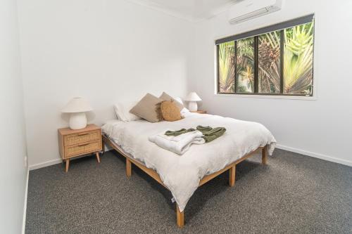 a bedroom with a bed with a night stand and a picture at Curlew Cove in Airlie Beach