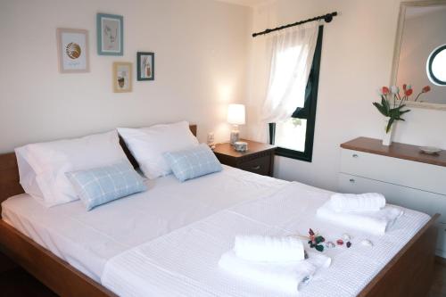 a bedroom with a bed with white sheets and blue pillows at CRYSTAL BAY in Paleo Tsifliki