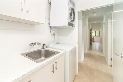 a white kitchen with a sink and a hallway at Curlew Cove in Airlie Beach