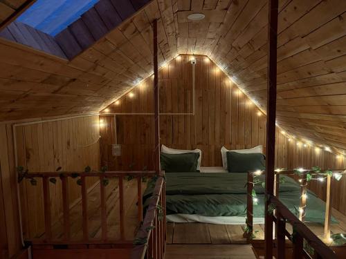 a bed in a wooden room with lights on it at Private Mudhouse Duplex Cottage by Kahani in Jibhi
