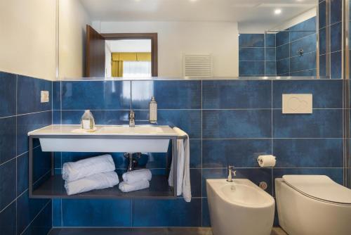 a blue tiled bathroom with a sink and a toilet at Best Western City Hotel in Bologna