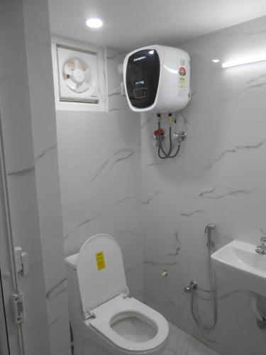 a white bathroom with a toilet and a sink at Sree jee stay in Varanasi
