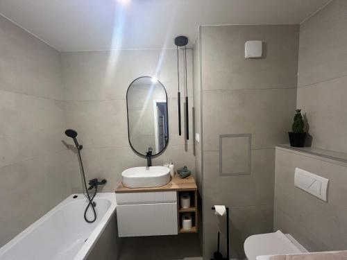 a bathroom with a sink and a mirror and a tub at Apartmán LÝRA Trenčín in Trenčín